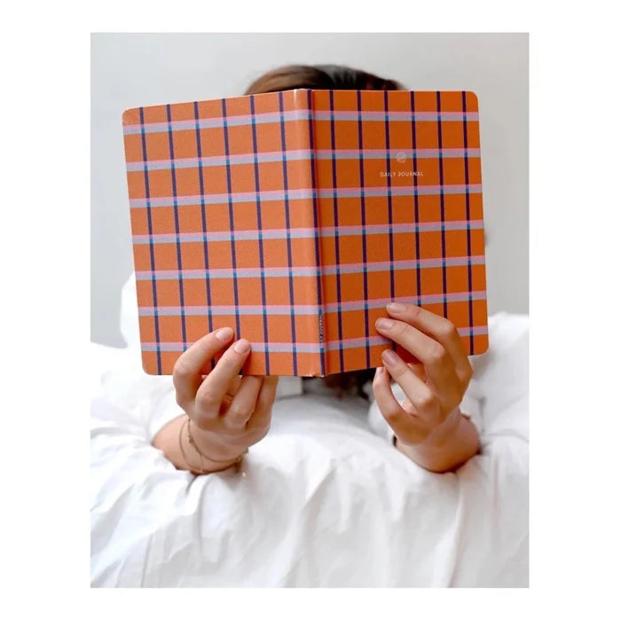 Person holding an A-Journal orange and blue checkered journal