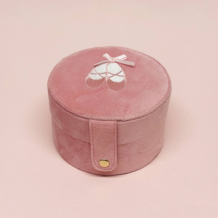 Pink round jewelry box with a bow on a pink background