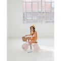 A child riding a pink Banwood toddler trike indoors with a big window in the background.