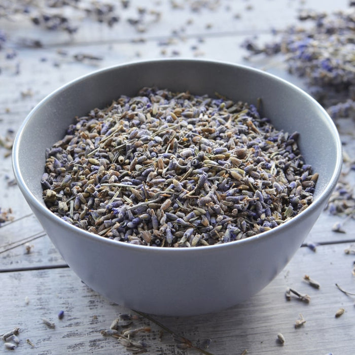 A gray bowl filled with dried lavender buds on a wooden surface, evoking a natural and calming aesthetic related to Bath & Body Oil | Privai skincare and wellness.