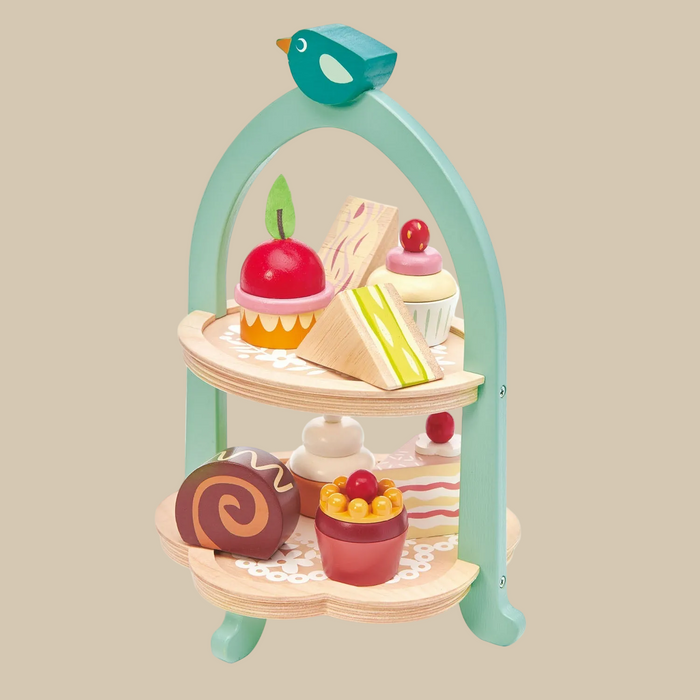 Wooden toy tea set with a three-tiered stand and colorful food items on a white background