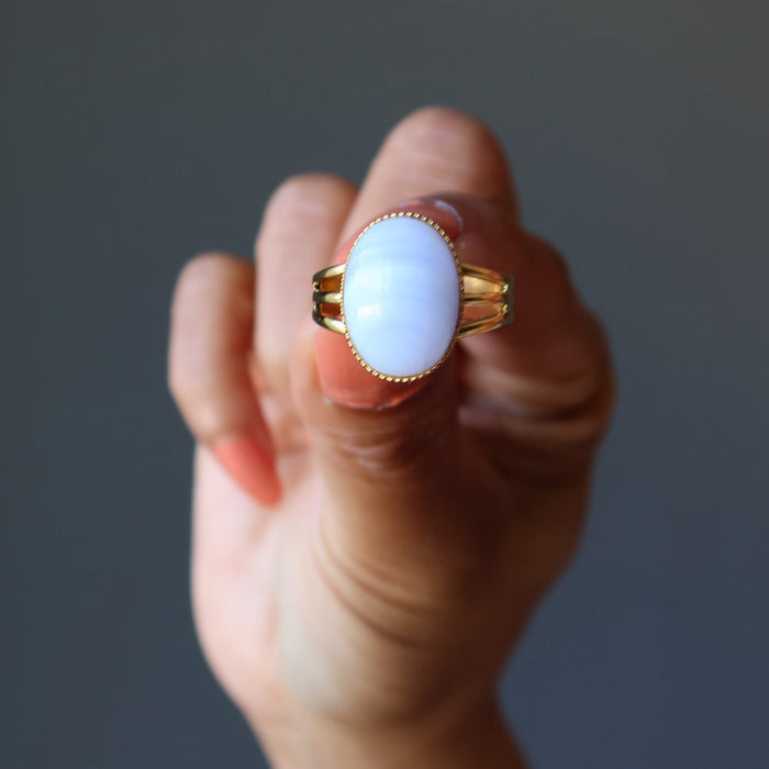 hand holding blue lace agate oval in gold tone adjustable ring