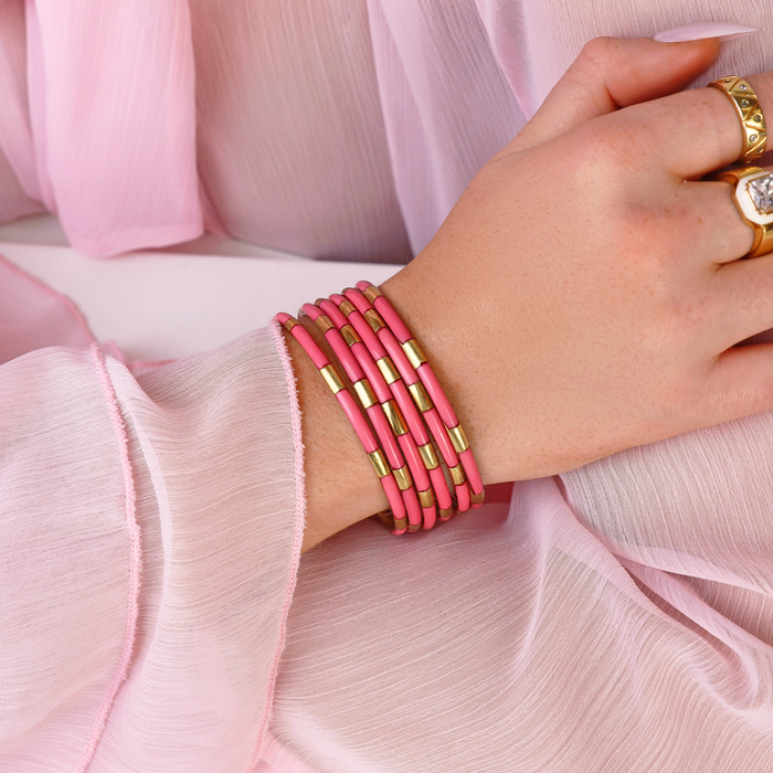 a hand with pink bracelets and rings