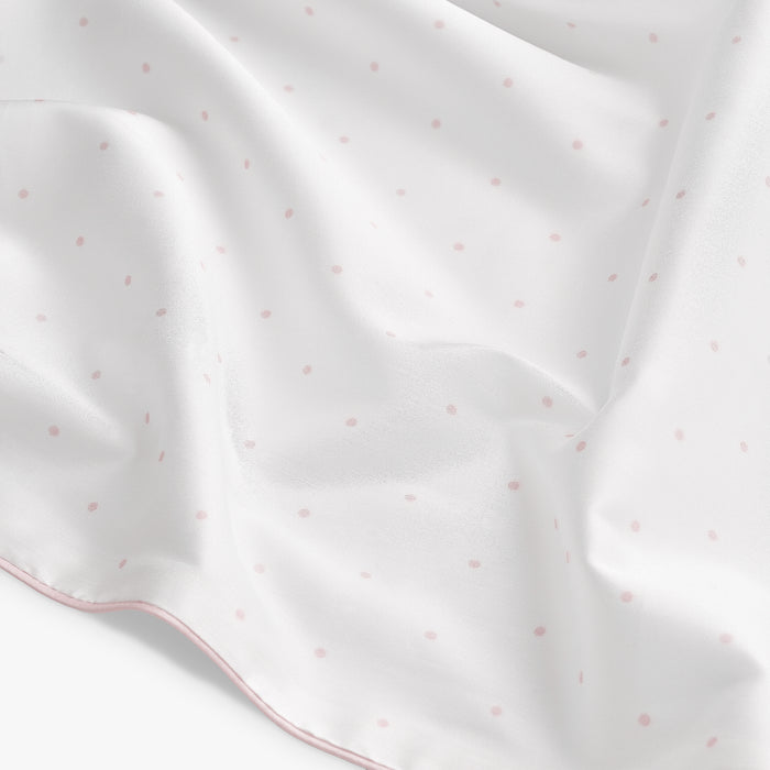 White fabric with pink polka dots on a white background