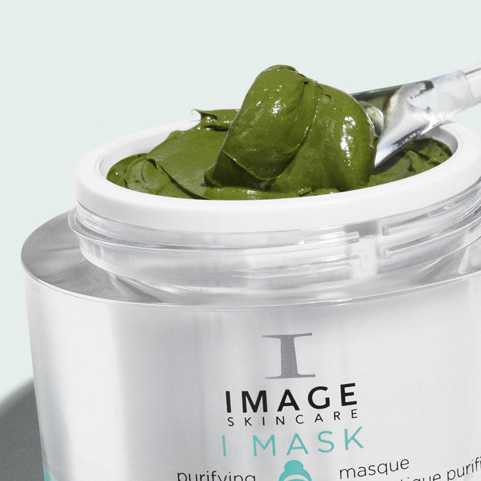Close-up of a jar with green creamy I MASK purifying probiotic mask | IMAGE Skincare being scooped with a small spatula, highlighting the smooth texture of the skincare product.