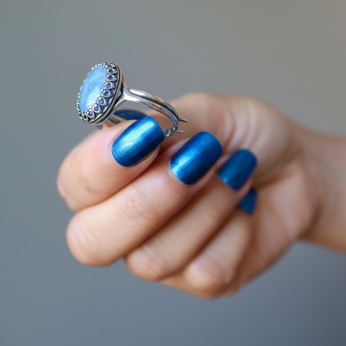 hand holding blue kyanite oval in adjustable sterling silver ring