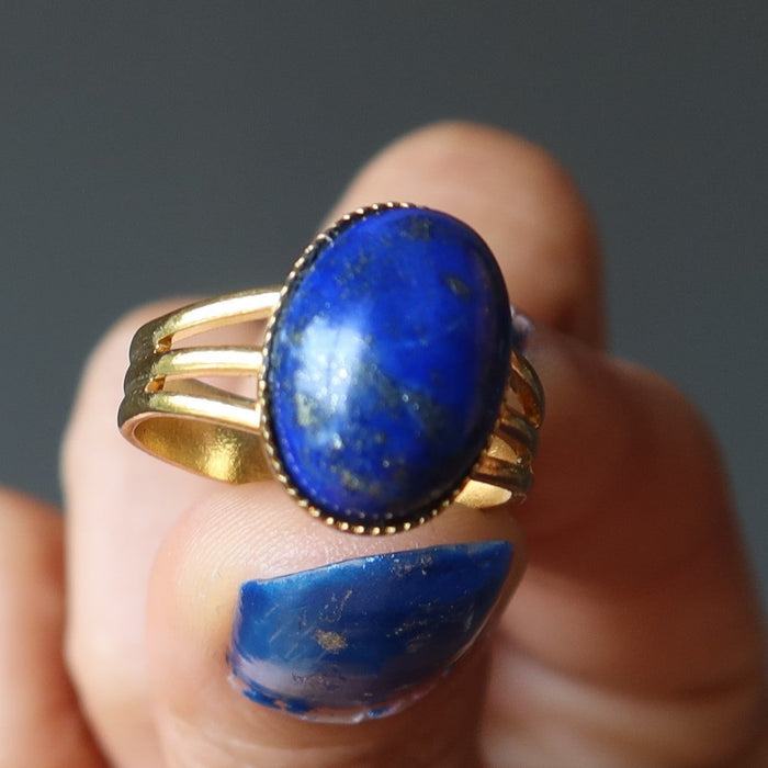 hand holding lapis lazuli gemstone in gold tone adjustable ring