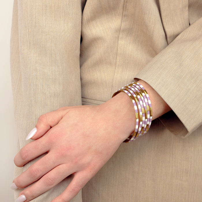 a woman wearing a beige jacket and bracelets