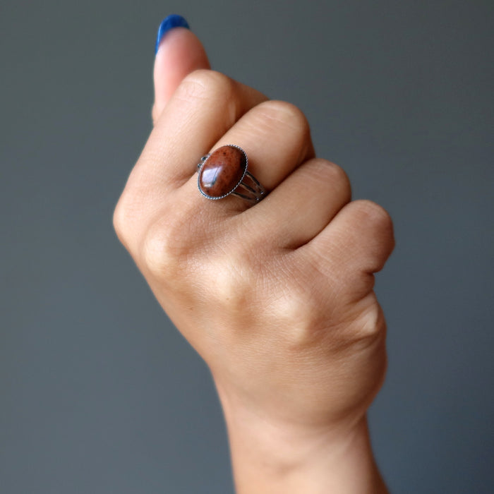 hand wearing mahogany obsidian oval in gunmetal adjustable ring