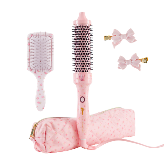 Pink hair styling set including a round brush, paddle brush, two bow hair clips, and a zippered pouch, all in a matching light pink floral pattern on a white background.
