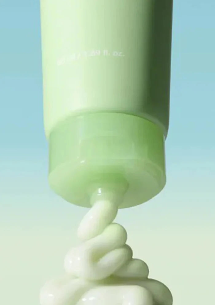 Green skincare product with cream being squeezed out on a gradient blue background