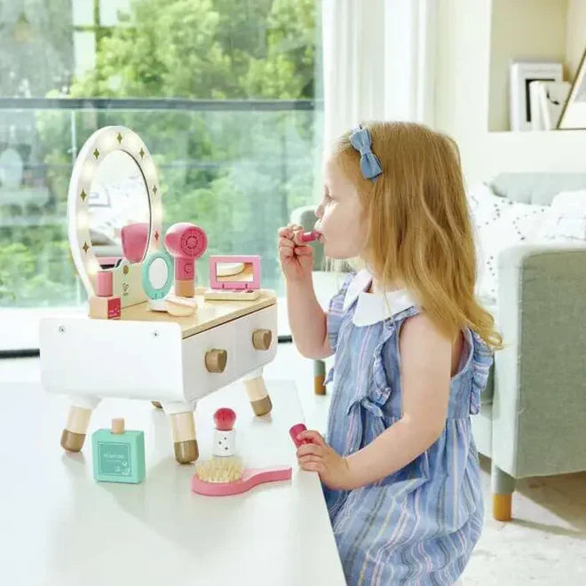 Child playing with a toy vanity set in a bright room