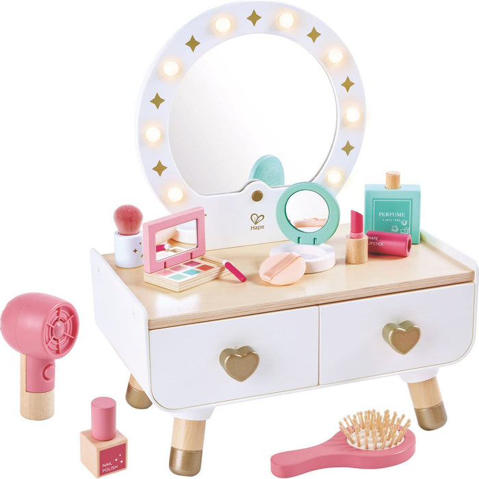 A light-up dressing table toy with a mirror, accessories, and a wooden base. The dressing table is primarily white with pink accents, and it features a mirror surrounded by star lights.