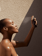 Woman with glowing skin sprays Natural Rehydrating Neroli Water 3.4 fl oz | Kerstin Florian on her face in sunlight for skincare and hydration.