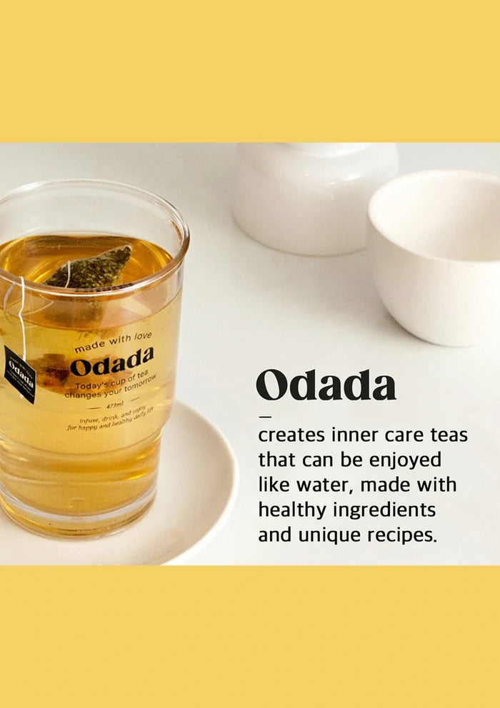 Glass of Odada tea with a tea bag on a white surface, featuring text about the brand and its teas.