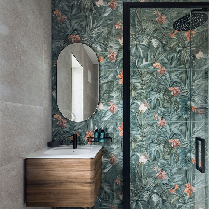 Bathroom with floral tiles, wooden vanity, and oval mirror.