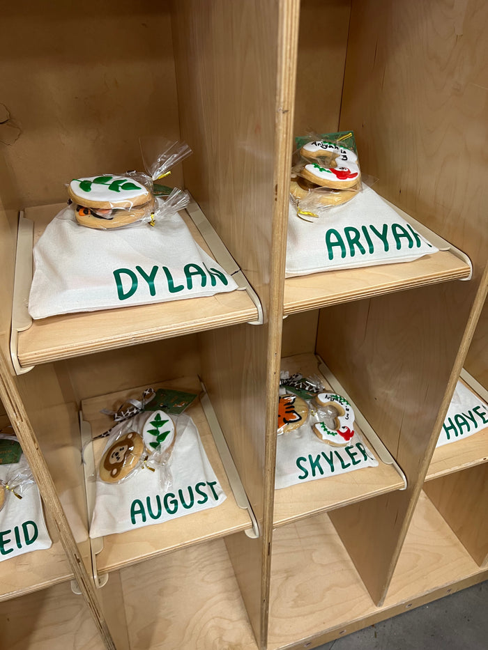 Wooden shelves with personalized name bags on a wooden floor.