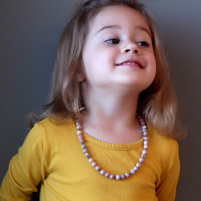 little girl modeling rhodochrosite necklace