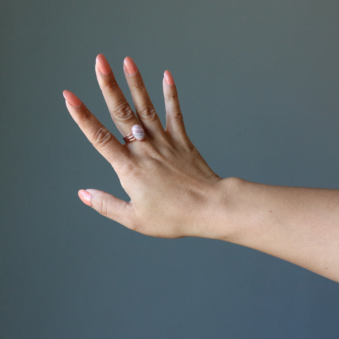 hand wearing pink rhodochrosite oval in adjustable copper ring
