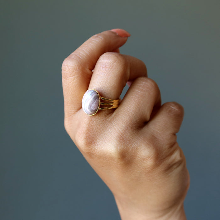 hand wearing rhodochrosite oval in gold adjustable ring