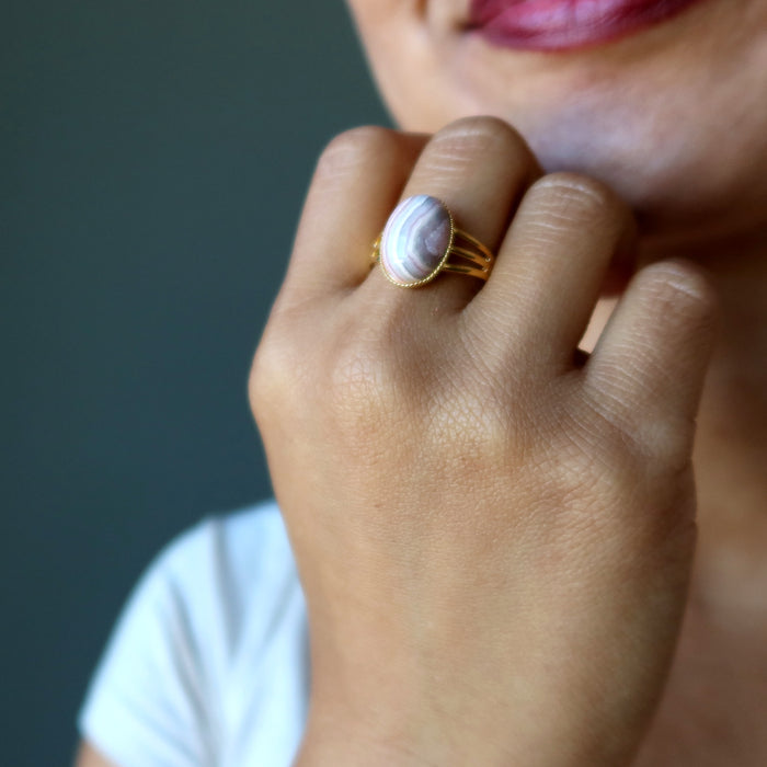 hand wearing rhodochrosite oval in gold adjustable ring