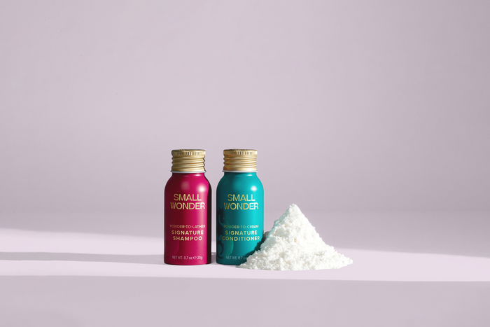 Two bottles of 'Small Wonder' Signature Shampoo & Conditioner with a pile of white powder.